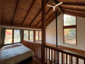 a bedroom with a ceiling fan and windows at Cabin A MtFuji view, BBQ, lake Saiko 3mins, hammock, wood deck in Narusawa