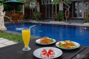 a table with plates of food and a glass of orange juice at La Semaya Beach Villas in Nusa Penida
