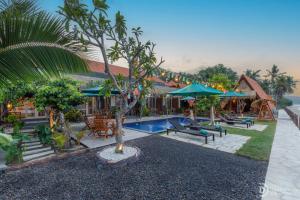 a resort with a pool and tables and umbrellas at La Semaya Beach Villas in Nusa Penida