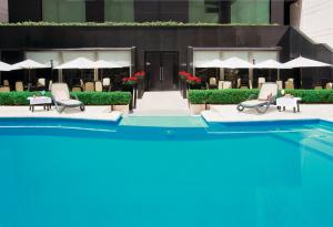 a pool with chairs and umbrellas in front of a building at Regal Pacific Puerto Madero in Buenos Aires