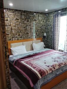a bed in a bedroom with a brick wall at Hotel Neilkanth in Dhanaulti