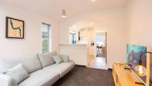 a living room with a white couch and a kitchen at Ruru Retreat- Free Parking- Hot Tub- Walk To Town in Queenstown