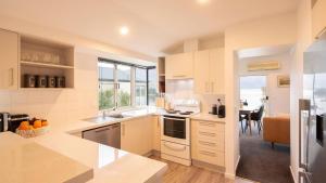 a kitchen with white appliances and a dining room at Ruru Retreat- Free Parking- Hot Tub- Walk To Town in Queenstown