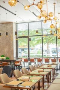 a restaurant with wooden tables and chairs and windows at Echarm Hotel Shenzhen World Exhibition and Convention Center in Fenghuangwei