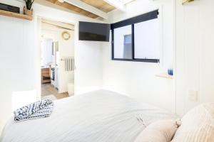 a white bedroom with a bed and a window at Tiny Home in the heart of Broadbeach-River Views! in Gold Coast