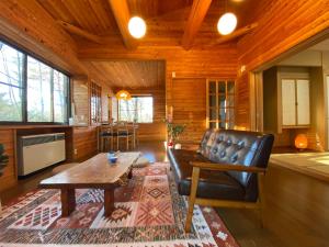 a living room with a leather couch and a table at 花の街660 Tsumagoi Private House with Parking & BBQ in Tsumagoi