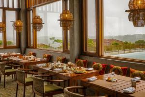 Greenpark Resort and Spa, Madikeri في ماديكيري: مطعم به طاولات وكراسي ونوافذ خشبية