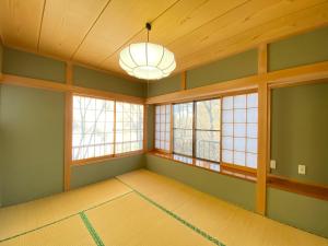 an empty room with windows and a light fixture at 花の街660 Tsumagoi Private House with Parking & BBQ in Tsumagoi
