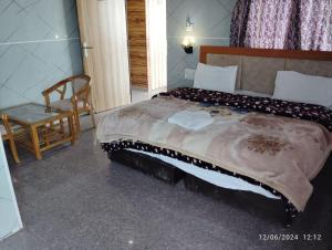 a bedroom with a bed and a table and a chair at Hotel Neilkanth in Dhanaulti +5 photos