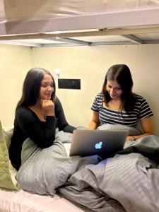two women sitting on a bed with a laptop at Konnect Inn-New Delhi Railway Station in New Delhi