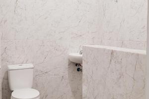 a white bathroom with a toilet and a sink at Urbanview Hotel Bonetta Lampung by RedDoorz in Kedaton +15 photos