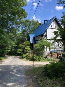 a house with a blue roof on the side of a road at Forest View Guesthouse in Omachi
