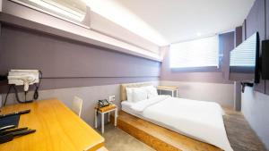 a bedroom with a bed and a desk and a television at NU Hotel in Cheonan