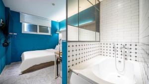a blue and white bathroom with a tub and a bed at NU Hotel in Cheonan
