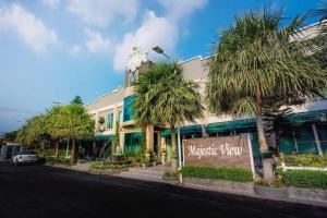 Un edificio con palmeras frente a una calle. en The Loom Rangsit, en Ban Lam Phak Kut