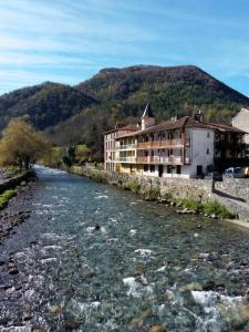 a river in front of a building next to a mountain at Au Songe Du Valier- Appartements in Seix