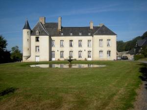 un gran castillo con un gran campo de hierba delante de él en Le Château d'Asnières en Bessin, en Asnières-en-Bessin