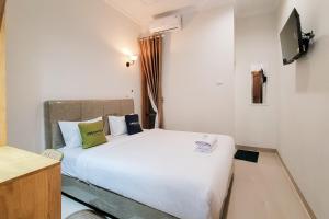 a bedroom with a large white bed and a television at Urbanview Hotel Bonetta Lampung by RedDoorz in Kedaton