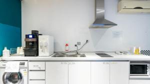 a kitchen with white cabinets and a sink and a stove at NU Hotel in Cheonan