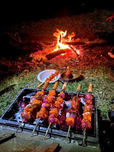 a bunch of food on a grill next to a fire at Top hill home stay in Sāma