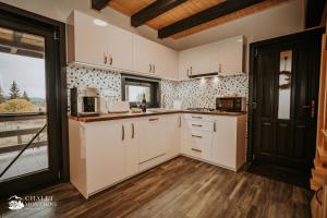 eine Küche mit weißen Schränken und einem großen Fenster in der Unterkunft Chalet Montagne Borzont in Bucsin