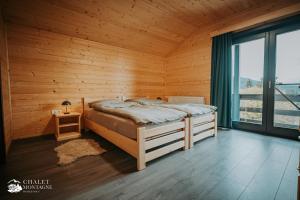 ein Schlafzimmer mit einem Bett in einem Holzzimmer in der Unterkunft Chalet Montagne Borzont in Bucsin
