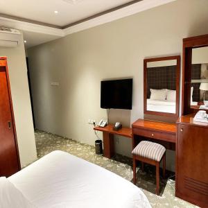 a bedroom with a bed and a desk with a mirror at Banan Ruz - شقق مخدومة in Hafr Al Baten