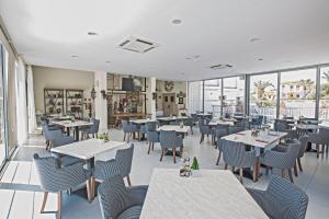 a restaurant with tables and chairs and windows at NissiLant hotel & suites in Ayia Napa