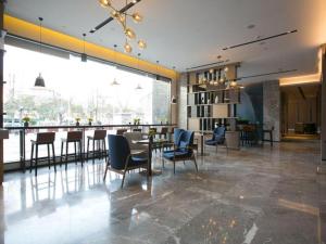 ein Restaurant mit Tischen und Stühlen und eine Bar in der Unterkunft Echarm Hotel Wuxi Zhongnan Road Ancient Canal in Wuxi