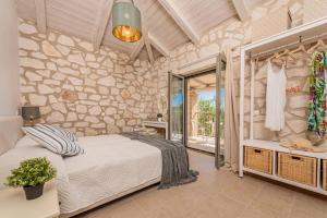 een slaapkamer met een bed en een stenen muur bij Villa Ionio Elia by Villa Plus in Vasilikos +18 foto's