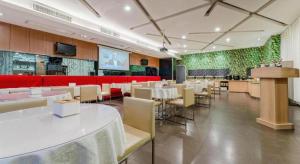 a restaurant with tables and chairs and a red couch at Zhangye Pinmu Hotel(Yuncheng Zhongyin Avenue Store) in Yuncheng