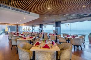 a restaurant with tables and chairs with a view of the ocean at Swiss-Belhotel Silae Palu in Palu