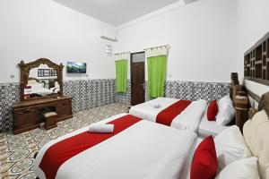 a bedroom with two beds and a mirror at RedDoorz Syariah Near Kantor Bupati Jepara in Jepara