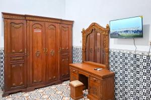 a room with wooden furniture and a tv on a wall at RedDoorz Syariah Near Kantor Bupati Jepara in Jepara