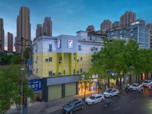 a building with cars parked on a city street at 7 Days Inn Wuhan Dingziqiao Zhongnan Road Metro Station in Wuhan
