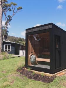 a black house with a window in a yard at Dune Shack - Beachfront - Sauna - Pet Friendly in White Beach