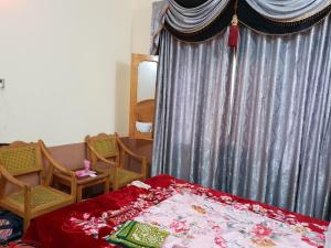 Un dormitorio con una cama con cortina y sillas. en Moon Rise Hotel, en Dargai