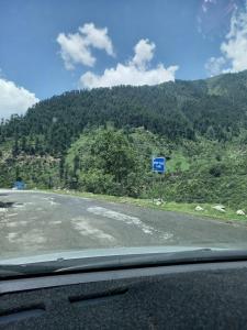 una carretera con una señal azul en la ladera de una montaña en Moon Rise Hotel, en Dargai