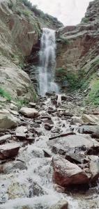 Una cascada con una persona parada frente a ella. en Moon Rise Hotel, en Dargai