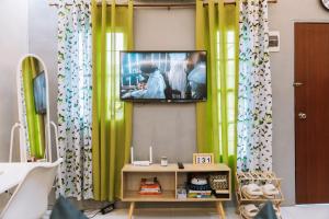 a television hanging on a wall with green curtains at JZ Homestay - Cozy Home near SM Savemore, Caraga State University & BMC Hospital in Butuan