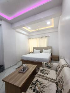 um quarto de hotel com duas camas, uma mesa e luzes roxas em Hotel Sanwariya em Gandhinagar mais 6 fotografias