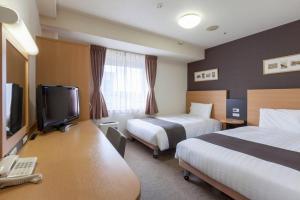 a hotel room with two beds and a flat screen tv at Comfort Hotel Yokohama Kannai in Yokohama