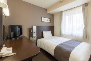 a hotel room with a bed and a desk with a telephone at Comfort Hotel Yokohama Kannai in Yokohama
