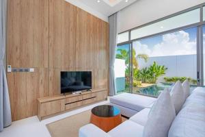 a living room with a white couch and a television at Escape Villa in Ban Bang Khu