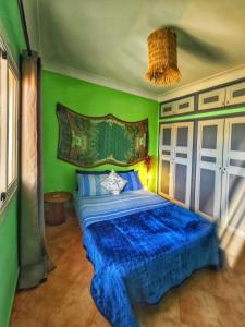 a bedroom with a blue bed with a green wall at Ocean Hideaway - Sea View in Essaouira
