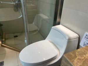une salle de bain avec toilettes et douche en verre dans l'établissement Shanghai Hongmin Inn, à Shanghai