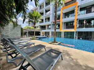 a swimming pool with lounge chairs in front of a building at 405 Relife , 5 Minutes Walk To Nai Harn Beach in Rawai Beach