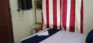 a bedroom with a bed with a curtain and a phone at Hotel O Sharan Guest House in Calcutta Bara Bazar