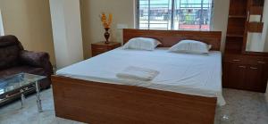 a bedroom with a large bed with white sheets and a chair at Hotel O Sharan Guest House in Calcutta Bara Bazar