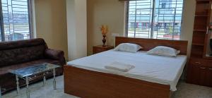 a bedroom with a bed with a couch and windows at Hotel O Sharan Guest House in Calcutta Bara Bazar